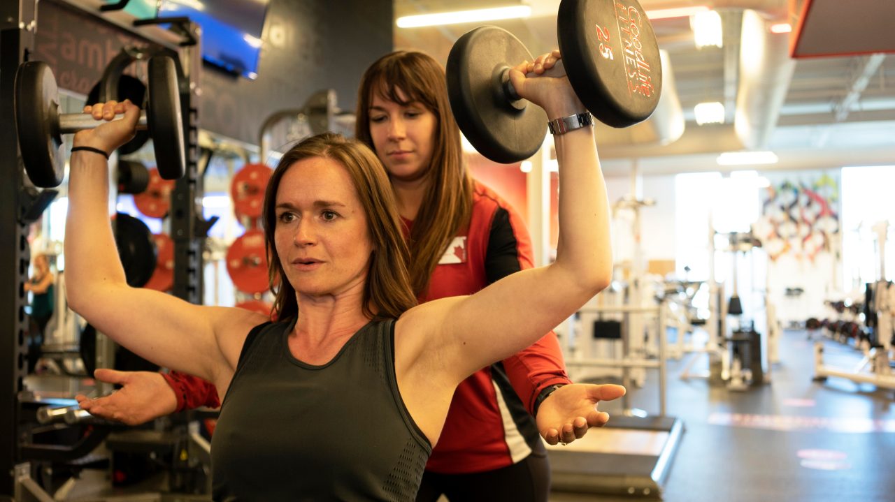GoodLife Fitness trainer observes a client doing a TRX pushup