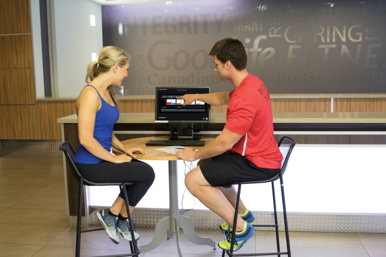 GoodLife Fitness trainer helps a client execute a bicep curl 