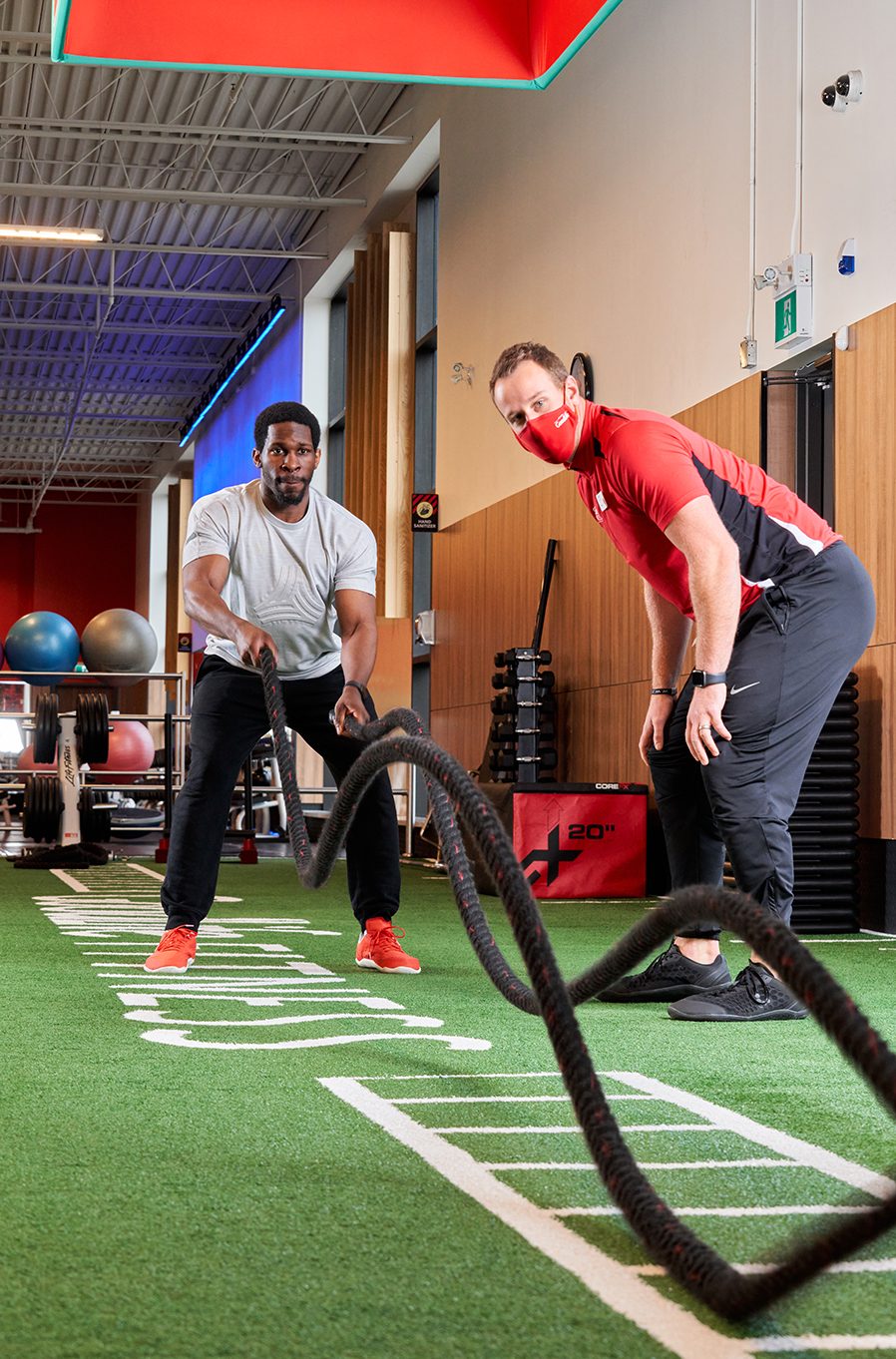 GoodLife Fitness trainer observes a client who is on an elliptical 