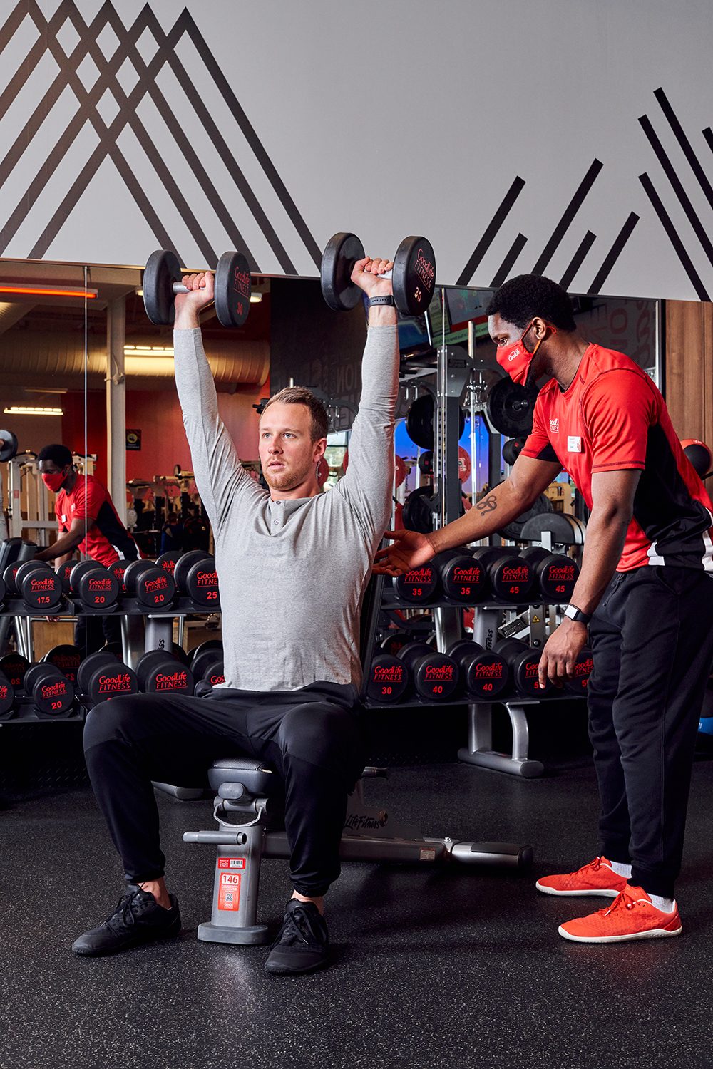 GoodLife Fitness trainer observes a client doing a TRX pushup